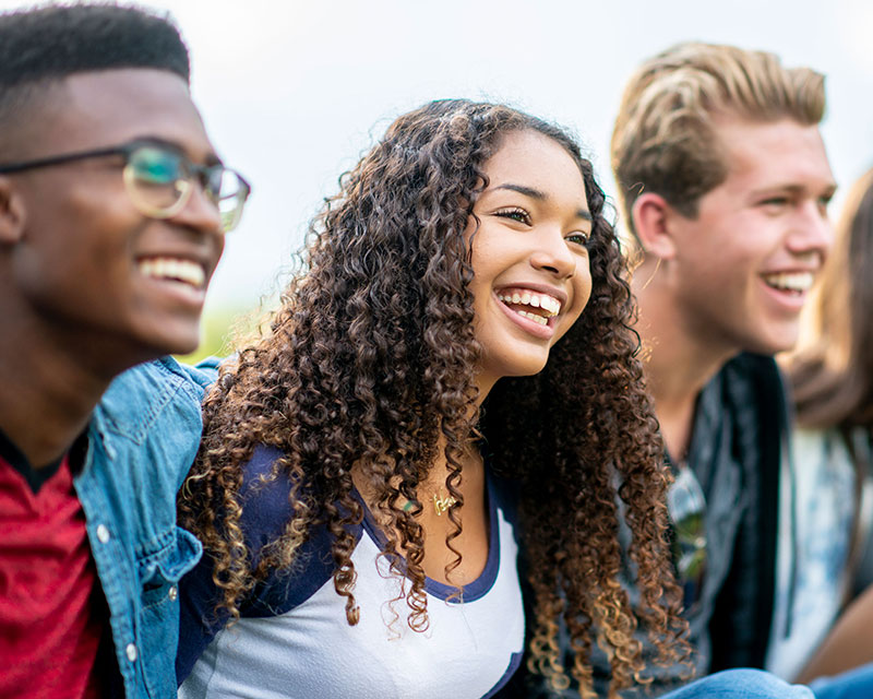 a group of teenagers smiling while outside